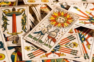 Crop view of many tarot cards disorderly lying on table with one with the sun and Le Soleil sign on top